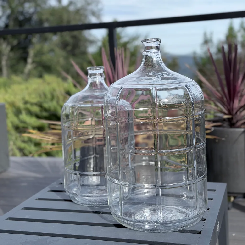 Two 5-gallon alkaline glass water bottles on an outdoor table